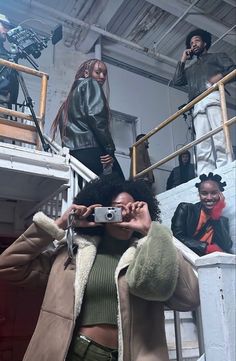 a woman taking a selfie with her cell phone in front of other people on stairs