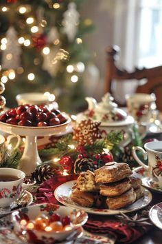 a table topped with plates and cups filled with desserts next to a christmas tree