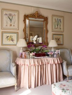 a living room filled with furniture and flowers on top of a table in front of a mirror