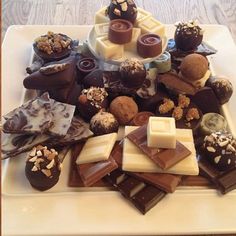 a white plate topped with lots of different types of chocolates on top of each other