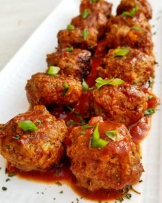 meatballs covered in marinara sauce and garnished with parsley on a white plate