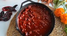 a pan filled with red sauce next to flowers