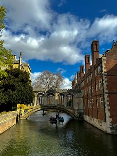 two boats floating down a river next to tall brick buildings on either side of a bridge