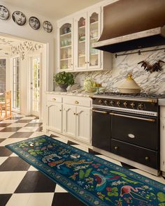 a kitchen with black and white checkered flooring, stove top oven and cabinets