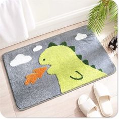 a pair of slippers sitting on the floor next to a rug with a dinosaur design