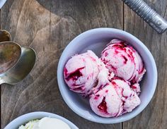 two bowls filled with ice cream next to spoons on top of a wooden table