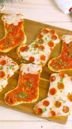 several pieces of bread with sauce and cheese on them sitting on a wooden cutting board