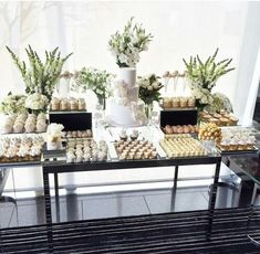 a table topped with lots of desserts next to a tall vase filled with flowers