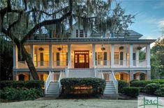 a large white house with trees and bushes around it