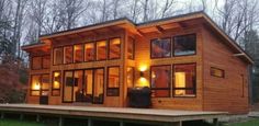 a small wooden house sitting on top of a lush green field in the woods at night