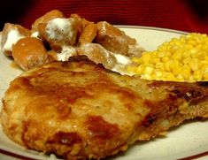 a white plate topped with meat, corn and other foods on top of each other