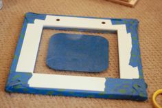 a blue and white frame sitting on top of a floor next to a pair of scissors