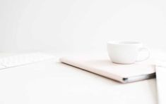 a white cup sitting on top of a computer keyboard