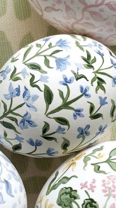 three painted eggs sitting next to each other on top of a cloth covered tablecloth