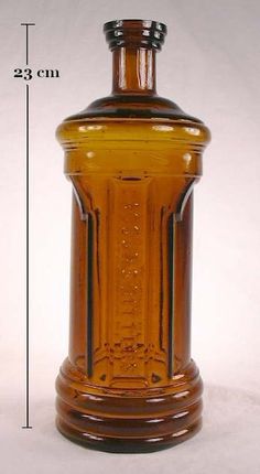 a brown glass bottle sitting on top of a white table next to a measuring ruler