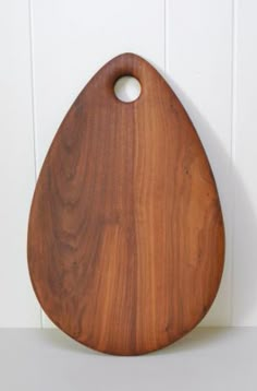 a wooden cutting board sitting on top of a white counter next to a wall mounted hook