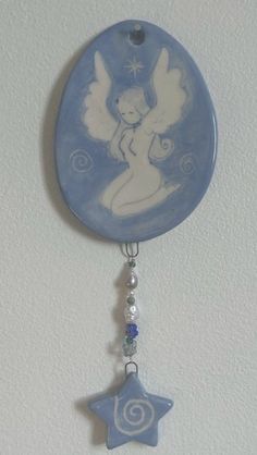 a blue and white decoration hanging from the ceiling with an angel on it's side