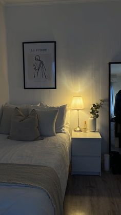 a white bed sitting next to a night stand with a lamp on top of it