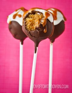 three chocolate covered candy lollipops with caramel drizzle on top