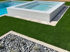 an empty swimming pool surrounded by grass and rocks