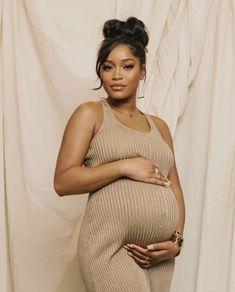 a pregnant woman poses in front of a white backdrop