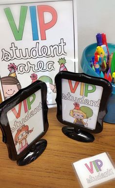 two black frames with pictures on them sitting on a table next to a sign and pencils