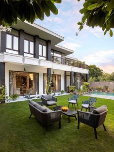 a lawn with chairs and tables in front of a large house that has a swimming pool