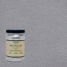 a jar of metallic paint sitting on top of a white wall next to a black cap