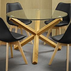 a glass table with four black chairs around it and a wall in the back ground