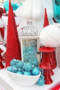 a table topped with red and blue christmas trees next to a white bowl filled with balls