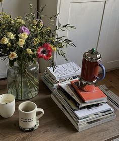 a glass vase filled with flowers sitting on top of a table next to a stack of books