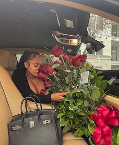 a woman is sitting in the back seat of a car with flowers and a purse