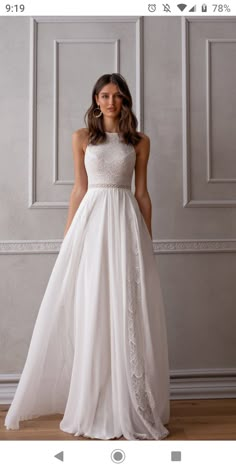 a woman in a white wedding dress standing on a wooden floor with her hands behind her back