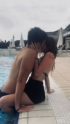 a man and woman kissing in front of a swimming pool