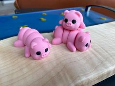 two pink pigs sitting on top of a wooden table