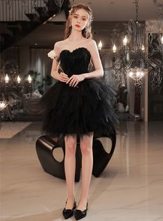 Make a bold fashion statement in this black short A-line gown. The fitted sweetheart corset bodice features intricate exposed boning and intricate appliques that create a unique and eye-catching look. The short fitted skirt is paired with an overlay of sheer tulle A-line skirt, adorned with matching appliques that beautifully complement the overall design. This is the perfect gown for a memorable event, sure to turn heads and leave a lasting impression. Feather Prom Dress, Sweetheart Corset, Corset Bodice, A Line Gown, Black Feathers, Fitted Skirt, Bold Fashion, A Line Skirt, Black Shorts