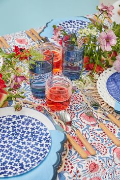 the table is set with blue and white plates, silverware, and pink flowers