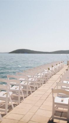 rows of white chairs sitting on top of a pier