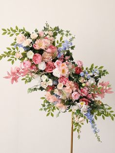 an arrangement of flowers on a stick in front of a white wall and flooring