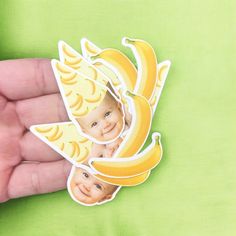 a hand holding a banana shaped sticker with two faces on it