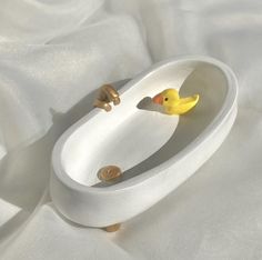 a yellow rubber duck in a bathtub on a white sheet with the lid down