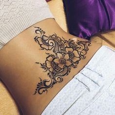 a woman's stomach with a tattoo design on the back of her stomach,