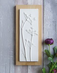 a white card with flowers on it sitting next to a purple flower and wooden frame