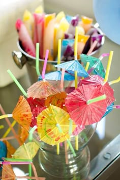 there are many colorful umbrellas in the vase on the table and one is filled with candles