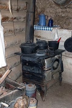 an old fashioned stove with pots and pans on it in a rustic kitchen area