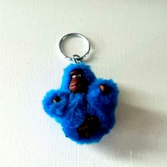 a blue stuffed animal keychain hanging on a white surface