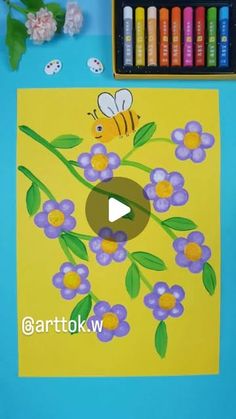 a painting with flowers and a bee on it next to some crayon markers