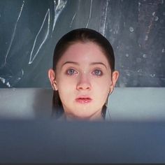 a woman in a bathtub looking at the camera with her eyes wide open and head tilted to the side