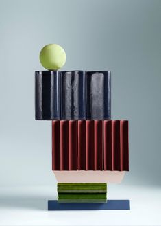 a sculpture made out of different colored blocks with an apple sitting on top of it