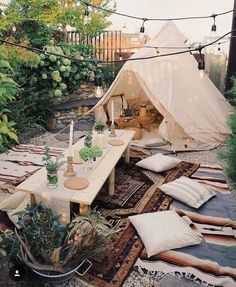 a tent is set up in the middle of a garden with lots of pillows and blankets